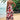 A woman wearing a pink geometric spaghetti strap maxi dress, suitable for summer wear. The dress is a one-piece garment with a fitted waist and flows down to a full length. She is standing outdoors, accessorized with sunglasses.