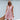 Sleeveless pink linen tiered mini dress with a V-neck design, worn by a smiling woman.