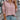 Light pink ribbed high-neck slim fit sweater for women, featuring streetwear style. The sweater is worn by a person with a focus on the shoulder and neck area, showcasing its comfortable fit and stylish design.