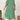 Plus size green loose fit midi dress with short sleeves, featuring an oversized casual design perfect for summer wear. The dress is displayed on a model standing and gesturing, highlighting the relaxed fit around the waist and knee length.