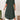 A woman standing and wearing a plus size green loose fit midi dress, ideal for casual summer wear. The dress features an oversized design with comfortable sleeves and a relaxed waistline, falling to a knee-length.