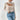 Ribbed high-neck cutout sweater in beige, featuring a chic turtleneck design, worn by a model in XL size. The sweater showcases a stylish cutout pattern on the shoulders and is paired with jeans. The model is accessorized with sunglasses, highlighting a casual yet trendy look.