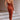Rust satin midi slip dress featuring a backless design with tie-back detail, showcasing an elegant and sophisticated style suitable for formal occasions.