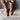 Rustic women's distressed brown leather mid-calf boots with a zipper, shown on a human leg, styled against a wooden backdrop with a flowerpot in the background.