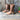Rustic women's distressed brown leather mid-calf boots with a zipper, set against a neutral background with subtle wood and plant elements.