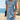 Woman wearing a light steel blue lace dress with short sleeves, fitted at the waist, reaching mid-thigh, suitable for casual summer beachwear.