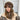 A woman wearing a brown sherpa baseball cap, styled as fashionable winter headgear, paired with a beige blazer.