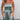A woman wearing a shimmery silver strapless metallic jumpsuit with a fitted waist, posing elegantly.