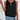 Sleeveless backless black top for women, perfect for casual summer fashion, paired with jeans.