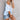 Woman wearing a striped blue and white V-neck summer blouse paired with distressed denim shorts.