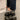 Stylish women's black platform orthopedic sandals with ankle strap, shown on a person wearing jeans, standing on a grey floor.