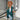 Teal long sleeve knit cardigan worn by a model, showcasing its fall fashion design with emphasis on shoulder, sleeve, and waist detailing. The cardigan appears to be part of a chic layered outfit suitable for cooler weather.