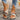 A pair of women's colorful bohemian espadrille flat sandals with ankle chain detailing, worn by a person in jeans.