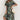 Tropical Leaf V-Neck Mini Dress featuring a bohemian style, perfect for summer resort wear. The dress has a flattering fit with a v-neckline and short sleeves, showcasing a vibrant tropical leaf pattern. The model is posed with her hand on her hip, highlighting the one-piece garment's silhouette.