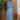 Turquoise linen asymmetrical hem long sleeve summer dress displayed on a standing mannequin, showcasing the fitted waist and flowing knee-length design.