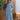 Turquoise linen summer dress with asymmetrical hem and long sleeves worn by a person standing, showcasing the dress's elegant design and vibrant azure color.