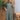 Turquoise linen dress with an asymmetrical hem and long sleeves, featuring a stylish summer design. The dress includes a defined waist and a collar, highlighting its one-piece garment structure.