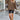 Urban Chic Brown Oversized Hooded Cape Sweater featuring a cozy design with a wide collar and long sleeves, modeled by a person wearing sunglasses. The sweater drapes comfortably around the waist and thighs, blending fashion-forward style with practicality.
