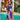 Woman wearing a vibrant print kaftan standing by the water, showcasing a luxury resort and tropical beach dress with green and azure patterns, featuring a relaxed fit with wide sleeves and a flowing waist.