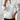 White cable knit zip-up sweater featuring long sleeves and a stylish design, suitable for women's autumn fashion.