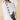 A white cross-stitch V-neck sweater for women, showcasing a bow-knot design at the waist, with long sleeves and a fashionable collar.