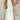 White halterneck tiered midi dress with sleeveless design, featuring a fitted waist and flowing skirt, ideal for elegant summer resort wear.