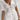 A woman wearing a white linen mini dress with short sleeves, a collar, and a lightweight, breathable fabric ideal for summer.
