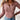 A woman wearing a white ribbed Henley blouse with long sleeves, showcasing a fitted style. The blouse is in a rose color and is size XL. The image highlights the neckline and shoulder area as part of the fashion detail.