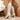 White ribbed high heel sock boots with a stylish block heel, shown in a fashion-forward winter outfit. The boots highlight a blend of comfort and elegance, featuring a sleek white design that reaches up to the knee.