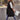 Women's beige hooded puffer vest, a stylish sleeveless winter coat, shown on a person standing, highlighting the vest's shoulder and waist design.