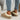 Women's black shearling fuzzy lined platform loafers worn with denim jeans, showcasing the stylish and comfortable footwear on a human leg.