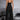 A woman standing and wearing a stylish black sleeveless wide-leg jumpsuit made of spandex, showcasing an urban summer fashion style.