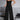 A woman wearing a black sleeveless wide-leg spandex jumpsuit, showcasing urban summer style, standing with a confident pose.