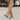 Women's brown suede slouchy knee-high boots in a bohemian fall style, shown on a model standing on a wooden floor, highlighting the knee and calf area.