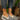 Women's brown wedge loafers, stylish casual sneakers, worn by a person standing on grass.