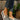 Women's brown wedge loafers styled as casual sneakers, worn on a person's feet with denim jeans, standing on grass.