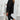 Woman wearing a black blazer, tailored trousers, and white trainers.