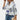A women's floral blouse featuring 3/4 sleeves and a V-neck design, in elegant white and purple colors.