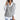 Women's gray cable knit V-neck sweater vest being worn, showcasing its chic, layered fashion style. The sweater vest is sleeveless with a V-neckline, perfect for layering over shirts or dresses. The cable knit pattern adds texture and interest to the garment.