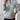 A light blue women's half-zip cable knit sweater featuring a spring fashion design, displayed on a mannequin with emphasis on the shoulder and arm areas.