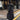 A woman wearing a long black puffer coat with a hood, walking on a city sidewalk.