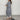 A woman wearing a long, flowy grey kimono cardigan, designed as a versatile summer wrap, showcasing its elegant drape over the shoulders and arms with loose sleeves, emphasizing a casual yet stylish look.