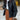Women's oversized black leather jacket in a casual street style fashion, featuring a structured shoulder and long sleeves, worn by a person standing and showcasing modern outerwear styling.