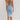 A woman wearing a sleeveless light wash denim bodycon midi dress that fits closely to the body, showcasing the arms and shoulders. The dress is a one-piece garment with a sheath style and is designed for day wear.