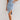 Sleeveless light wash denim bodycon midi dress worn by a woman with loose hair, featuring a sheath silhouette and a casual day dress style.
