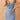 A woman wearing a sleeveless light wash denim bodycon midi dress. The dress is form-fitting, highlighting the waist and extending to a midi length, with a simple round neckline.