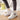 Women's stylish pink high-top sneakers shown on a person's feet, highlighting their trendy design and comfortable fit.