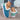 Women's turquoise fur-lined slip-on shoes paired with denim jeans, highlighting stylish winter footwear on a person's legs.