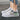 Women's white lace-up sneakers with a low-top design and durable sole, featuring subtle grey and black accents, displayed on grass.