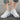 White lace-up women's sneakers with a low-top design and durable sole, shown from a side angle. The sneakers are stylish and suitable for casual wear.